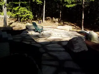 Sunlit fire pit patio with green chair