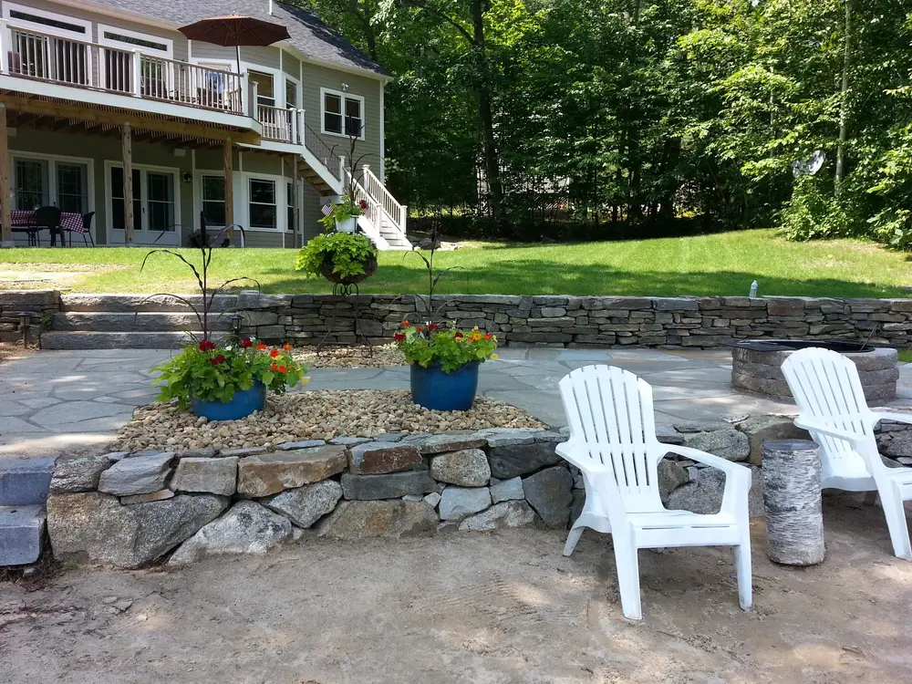 Terraced stone wall patio with fire pit and flowers