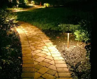 Lit paver path with garden lighting at night