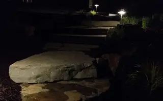 Lit stone steps and boulder at night