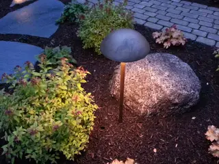 Path light beside boulder and stone walkway