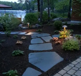 Path lights along stepping-stone walkway near lake