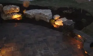Uplit boulders along paver patio wall