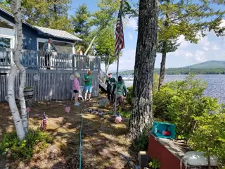 Crew and homeowners gather by lake flagpole