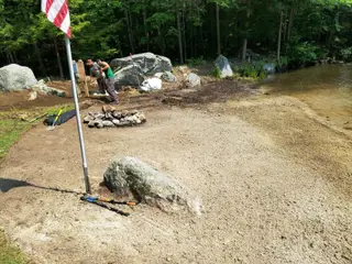 Crew building stone fire pit at water's edge