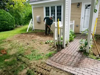 Crew digging planting bed by brick walkway