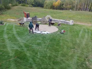 Crew installing flagstone patio inside stone fire pit wall