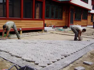 Crew laying cobblestone paver patio