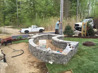 Crew member building stone fire pit wall