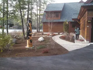 Crew raking new paver walkway at log home entrance