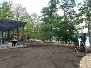 Crew raking soil for lakeside lawn