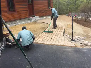 Crew sweeping newly laid paver walkway