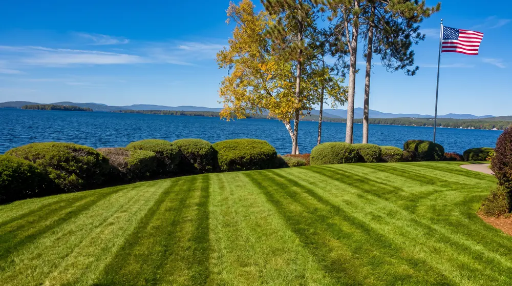 Lakefront lawn overlooking the Lakes Region mountains with an American flag