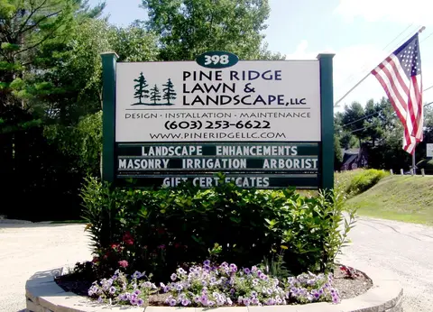Pine Ridge Lawn and Landscape entrance sign beside an American flag