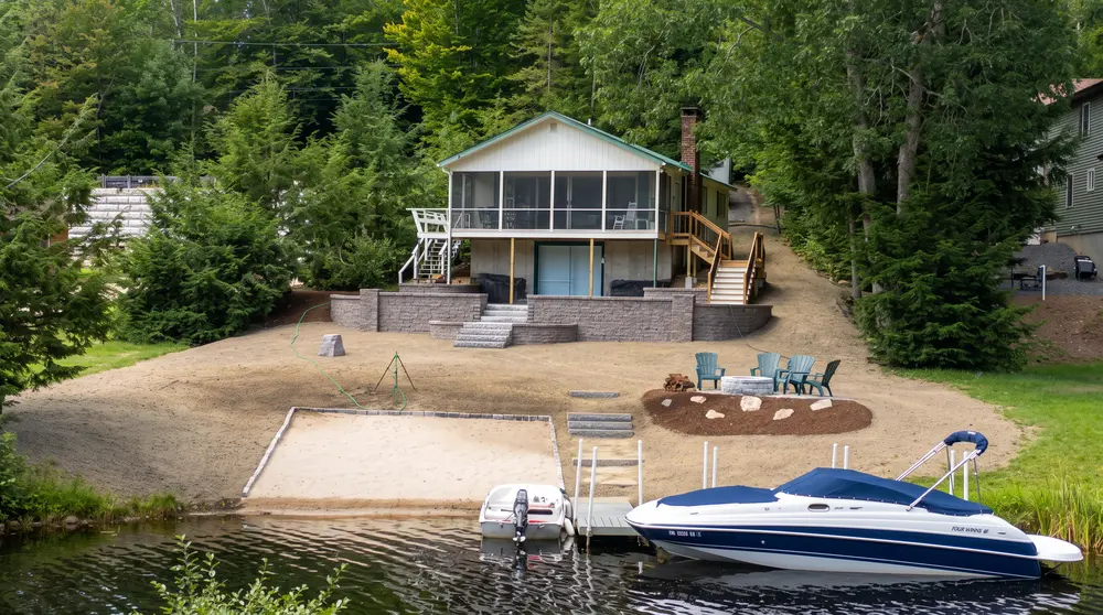 Lakefront home with a new stone retaining wall, stairs, landscaped shore, and boat dock