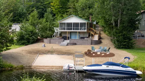 Lakefront home with a new stone retaining wall, stairs, landscaped shore, and boat dock