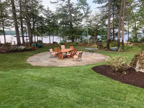 Lakeside dining patio with a wooden table and chairs