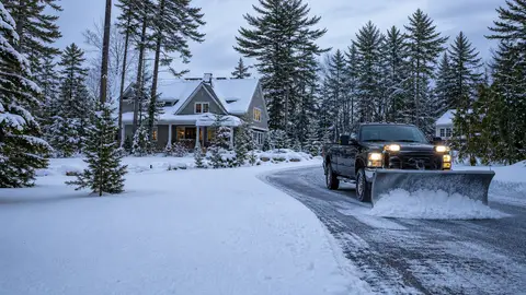 Snowplow clearing a freshly cleared driveway at a Lakes Region home