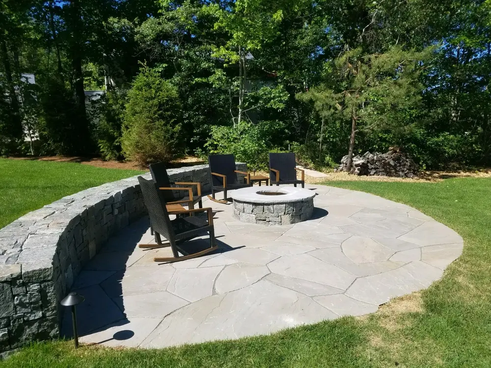 Outdoor stone patio with chairs around a fire pit
